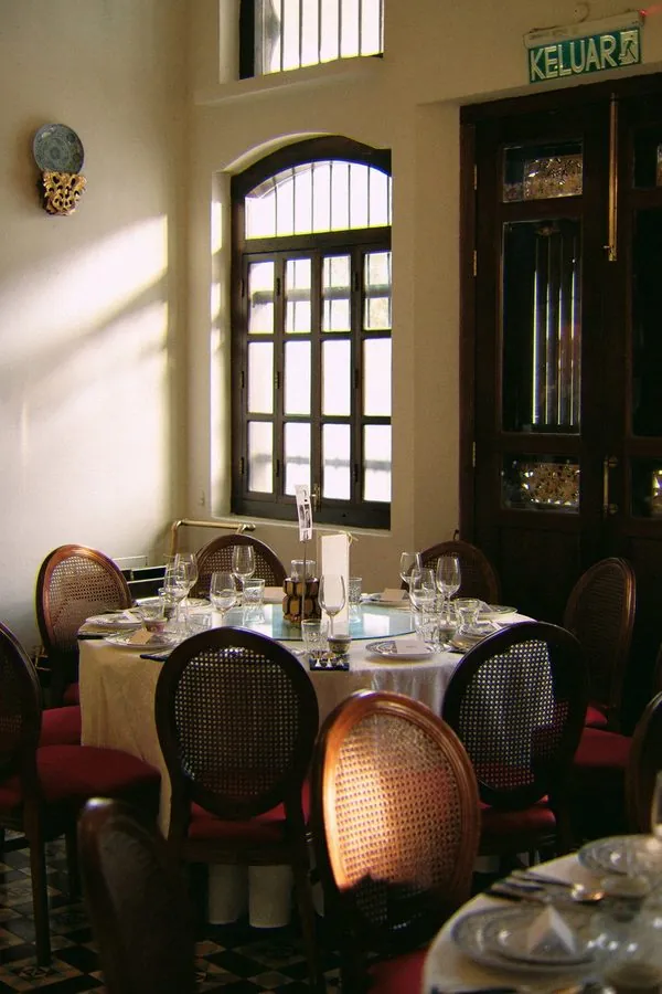 Afternoon light falling across a round wedding banquet table by an arched window