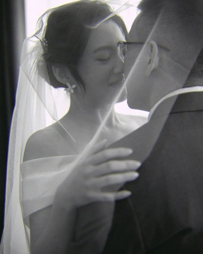 Black and white portrait of a bride and groom under her veil