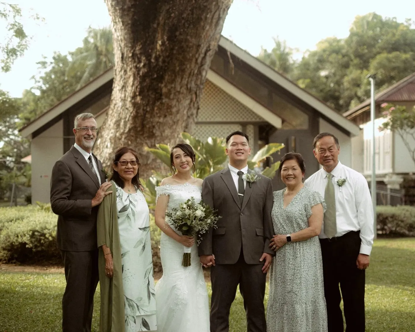 Bride and groom with both their families on the lawn after their wedding ceremony