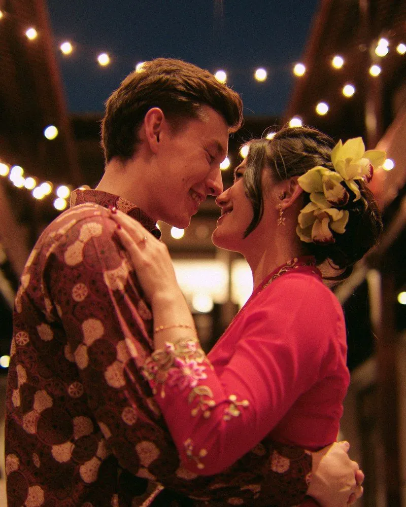 Couple embracing under festoon lights at their wedding dinner