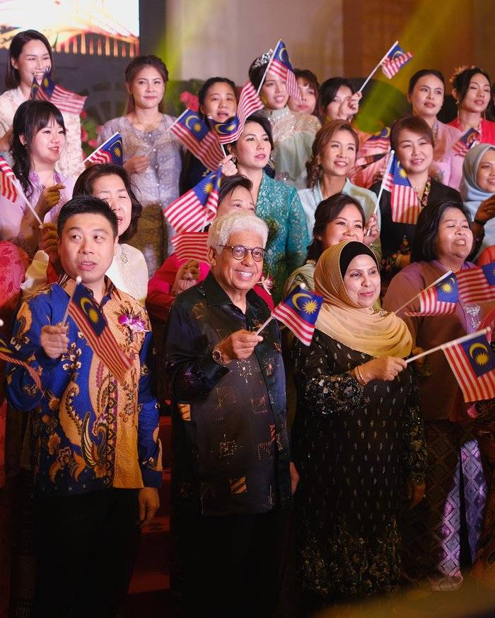 Event photographer in Penang capturing a group celebration with Malaysian flags at a formal event