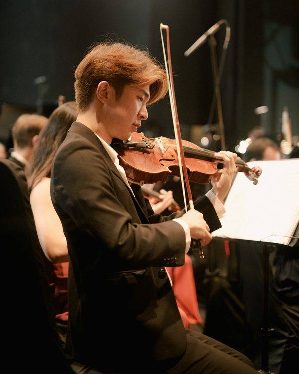 Penang event photographer capturing a violinist performing with an orchestra