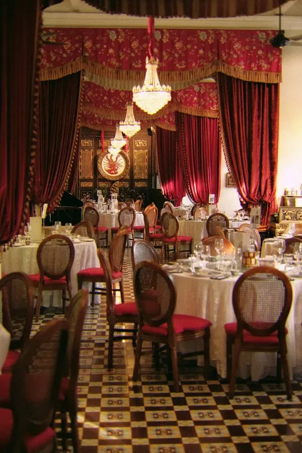 Peranakan wedding dinner hall with crystal chandeliers, red velvet drapes and cane-back chairs in George Town